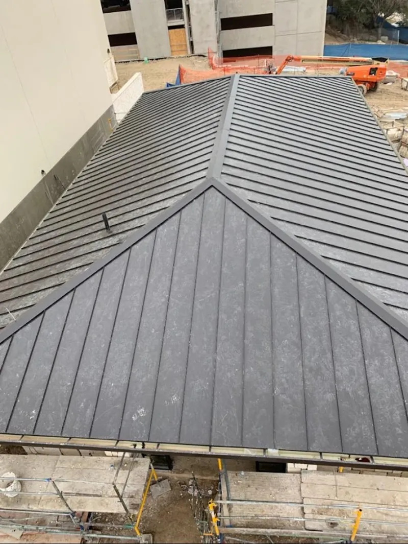 Commercial metal roof construction with crane equipment in Frisco